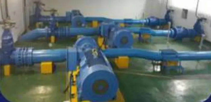 Blue pump sets and suction pipework alongside a water channel at a treatment works